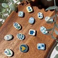 Detail showing various handmade ceramic moon and star pendants on a wooden background