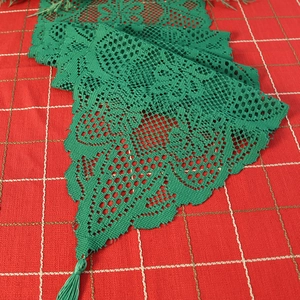 Green Christmas tree lace table runner with tassels on a festive red plaid background