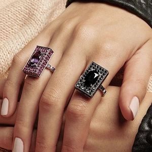 Wide square band rings with purple and black gemstones, worn by a model in a close-up