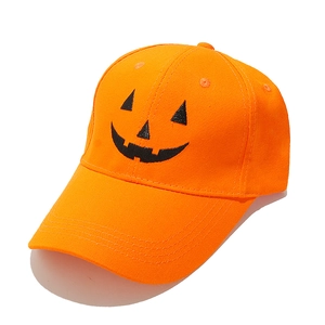 Detailed view of the orange cotton baseball cap featuring a black Halloween pumpkin face