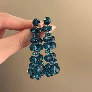 Detailed view of long dark blue beaded tassel earrings with faceted crystals on hand