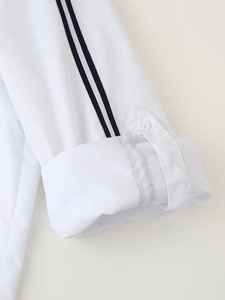Detail of white shirt sleeve featuring contrast striped webbing and button tab closure