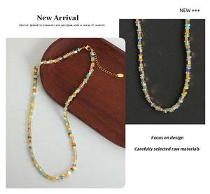 Détail de perles en pierres naturelles multicolores sur collier en acier titane doré