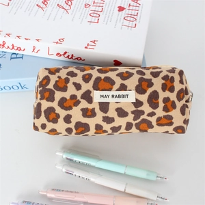 Detail of leopard print corduroy pencil case with woven brand logo in a desk scene