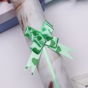 Macro detail of green heart pattern ribbon bow for festive gift packaging and decoration