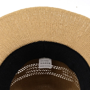 Detail view of woven paper straw hat interior showing sweatband and 100% paper material label