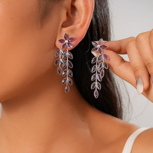 Retro purple glass flower and leaf tassel earrings on a model in a close-up shot