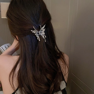 Close-up of a silver liquid metal butterfly hair claw clip on dark brown wavy hair
