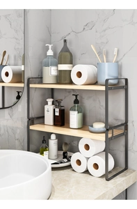 Detail of a 2-tier black metal bathroom organizer with wood grain shelves on a marble counter