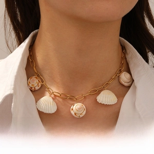 Detail of gold seashell necklace with scallop and conch pendants on model's neck