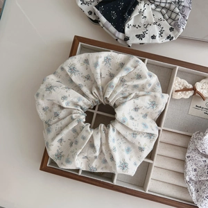 Close-up of floral print cotton scrunchie with blue patterns in a wooden tray