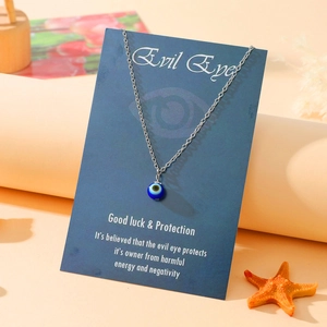Detailed view of silver stainless steel evil eye necklace with blue charm on display card