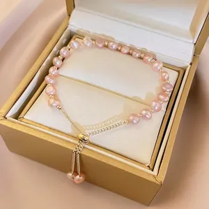 Detailed close-up of pink baroque pearl bracelet with gold beads in premium gift box