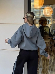 Dettaglio felpa con cappuccio grigio scuro e pantaloni neri con striscia laterale casual