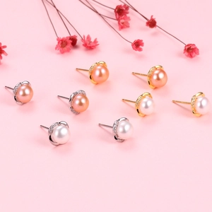 Detail of S925 silver crown earrings with natural white and pink pearls on pink background