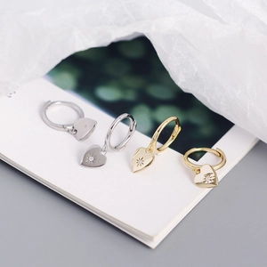 Macro shot of silver and gold heart pendant hoop earrings with starburst zircon details