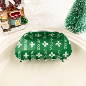 Gros plan sur la pince à cheveux de Noël verte avec texte Merry et motifs flocons