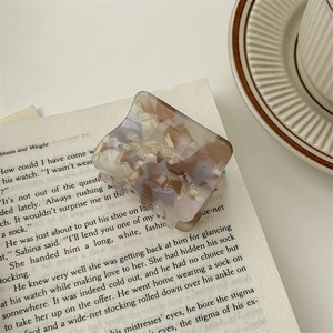 Detail of a square star tortoise shell hair claw clip on an open vintage book page