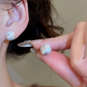 Detail of minimalist brushed spherical stud earrings with silver-grey matte finish