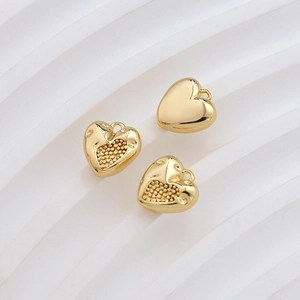 Macro detail of heart-shaped gold-plated pendants with textured dots and smooth finishes