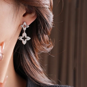 Silver plated double clover drop earrings with beaded edges worn by a model