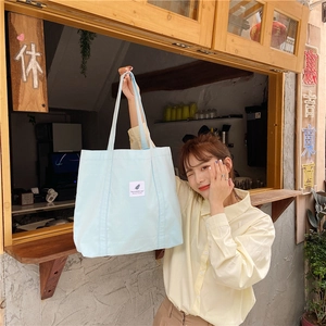 Light blue canvas tote bag shown with a model in a vintage aesthetic street setting