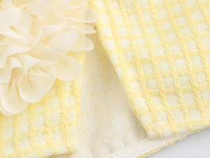 Dettaglio fiore 3D in rete su minigonna in tweed giallo chiaro con trama a quadri