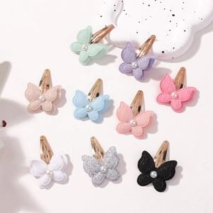 Flat lay of colorful glittery butterfly hair clips with central pearl accents for girls