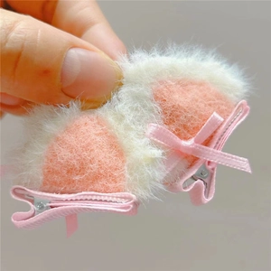 Close-up of plush cat ear hair clips with pink ribbon bows and metal alligator clips