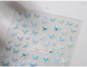 Detailed close-up of iridescent blue butterfly nail stickers with 3D crystal accents