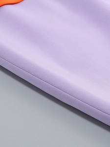 Close-up of purple suit dress with orange piping and fine textured stitching detail