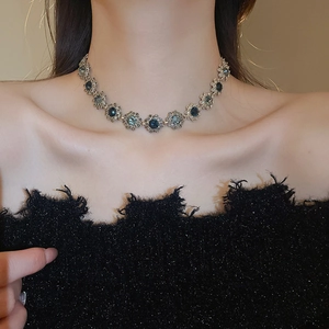 Close-up of vintage silver necklace featuring teal flower gemstone pendant on model