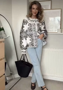 Détail d'une veste blanche pour femme avec broderie noire et motif miroir chic