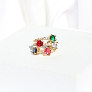 Detail van vergulde meerlaagse ring met vijf gekleurde stenen op een witte stenen basis