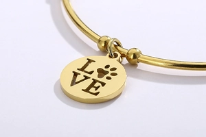 Detailed close-up of golden stainless steel bracelet featuring a heart LOVE charm