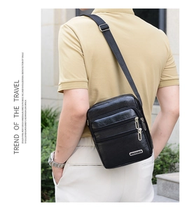 Outdoor shot of men's black faux leather crossbody bag with multiple zip compartments