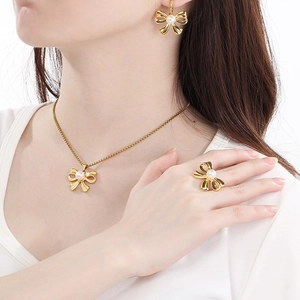 Elegant gold bow jewelry set with pearls featuring necklace earrings and ring on model