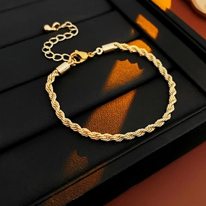 Detail of gold twisted rope chain bracelet with lobster clasp and round ball charm