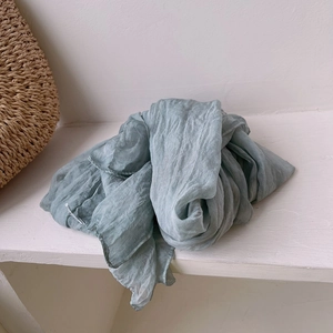 Detail shot of light green pleated silk scarf with semi-transparent crinkle texture