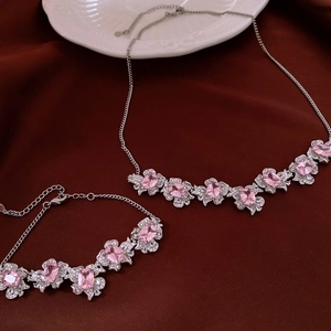 Close-up of silver necklace and bracelet set with pink zircon floral pendant and stones
