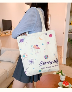 Detail of white canvas tote bag with colorful starry sky print and starry slogans