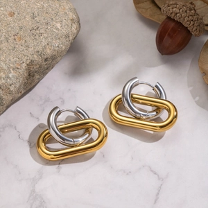 Close-up of interlocking gold and silver geometric hoops on white marble background