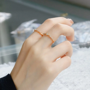 Close-up of dual gold rings with opal and tiny diamonds on a finger with lace backdrop