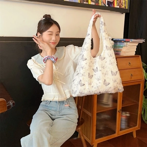 Detail of white plush tote bag featuring gray butterfly patterns and soft faux fur texture