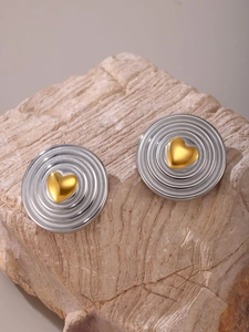 Detailed view of heart-shaped earrings with gold center and silver wavy texture