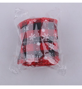 Close-up of red and black buffalo plaid Christmas ribbon roll with white snowflake print