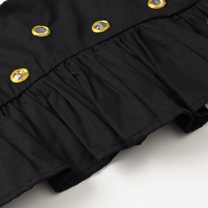 Détail du tissu noir avec des boutons dorés décoratifs et des finitions à volants