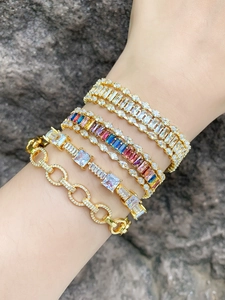 Gros plan de bracelets multicouches dorés avec zircons colorés portés par un mannequin