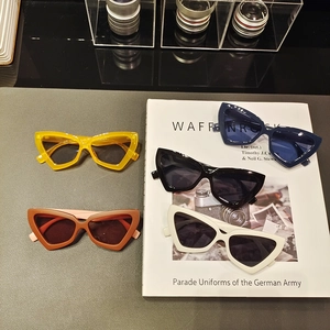 Flat lay of retro triangle cat-eye sunglasses in yellow, red, black, and white colors