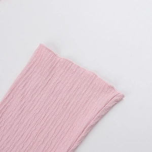 Detailed close-up of pink knit fabric with elegant pleated texture on the sleeve cuff